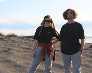 Zoey and Maru on beach wearing Origin Organic Cotton Joggers, Zoey in a small, Maru in a large. Certified, ethically made in factory powered by solar and wind energy